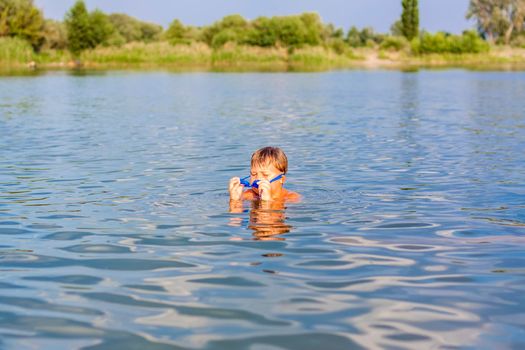 A happy child is swimming in the river on a very hot summer day. Swim in reservoirs. A happy family has fun and splashes in the water in the summer. Family on vacation