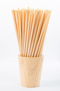 Wheat straw for drinking water in wooden glass on white background. Zero waste concept.
