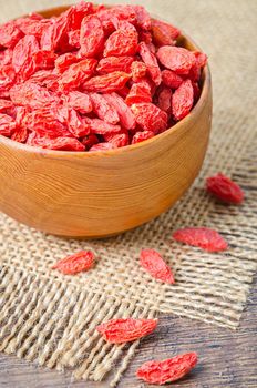 Dried Chinese wolfberries or goji berries in wooden cup.
