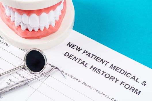 New patient medical form with model tooth and dental instruments. Dental health and teeth care concept.