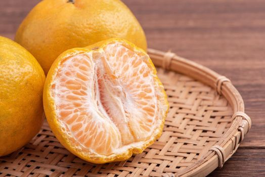 Fresh, beautiful orange color tangerine on bamboo sieve over dark wooden table. Seasonal, traditional fruit of Chinese lunar new year, close up.