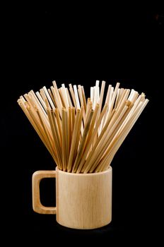 Wheat straw for drinking water in wooden glass on black background. Zero waste concept.