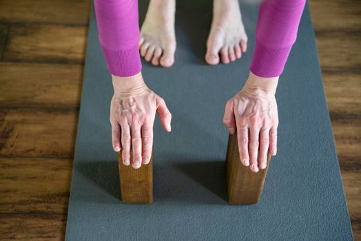 Women practicing yoga therapy, stretching in down dog using blocks and the wall, downward facing dog, exercise for spine and shoulders flexibility, working out, closeup