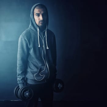 I stay strong. Studio portrait of a young man working out against a dark background