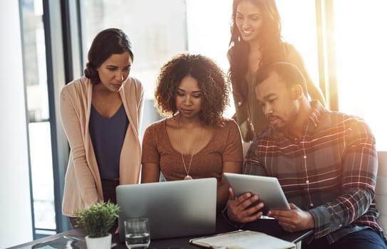 Connecting as a team online and offline. a group of young professionals using wireless technology together in a meeting