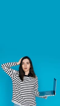 Emotional Young Woman in Striped Sweater Distraught by Bad News on Laptop - Expressive Female Feeling Sad and Disheartened - Isolated Blue Background - Perfect for Conceptual, Emotional,