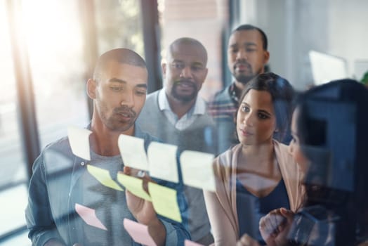 This is where success is made. High angle shot of a group of coworkers brainstorming on a glass wall