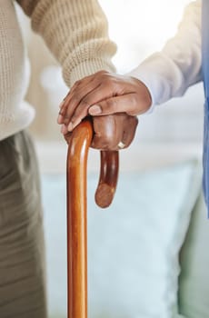 Elderly patient, cane and nurse holding hands for support, healthcare and kindness at nursing home. Senior person and caregiver together for homecare, rehabilitation or help for health in retirement.
