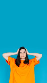 Stressed Young Woman Expressing Discontent, Touching Head - Negative Emotions, Frustration, Isolated Blue Background.