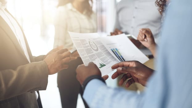 The latest stats are in. Closeup shot of a group of businesspeople going through paperwork in an office