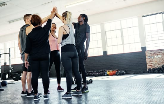 Sticking together. a cheerful young group of people forming a huddle together before a workout session in a gym