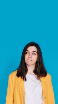 Serene Young Woman Contemplating, Gazing into Empty Space, Thoughtful Young Woman in Captivating Portrait, Lost in Contemplation, Isolated on Blue Background.