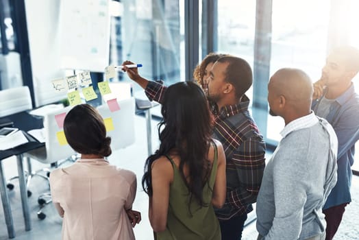 Taking them through the gameplan. High angle shot of a group of coworkers brainstorming on a glass wall