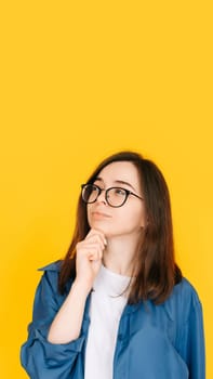 Smart Shopping Decision: Stylish and Thoughtful Woman Considering New Product Purchase, Arm on Face Pose - Fashionable Consumer Concept Isolated on Yellow Background.