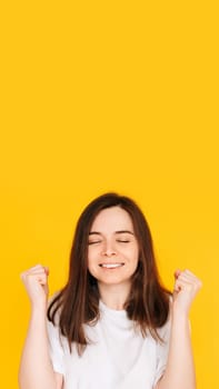 Exhilarated Woman Celebrating Big Win with Raised Fists - Excitement, Victory, and Financial Success Concept on Vibrant Yellow Background.