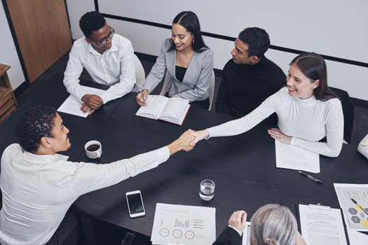 Business people, handshake and teamwork in meeting for partnership, corporate growth or deal above at the office. Happy employees shaking hands for b2b, agreement or introduction at the workplace.