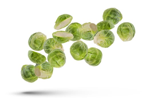 Green Brussels sprouts on a white isolated background. Flying vegetables isolated on white. Scatter a set of cabbage in different directions. Tasty and healthy food concept.