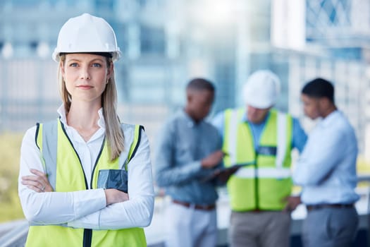 Portrait, arms crossed and a serious woman construction worker outdoor on a building site with her team in the background. Management, leadership and a confident female architect standing outside.