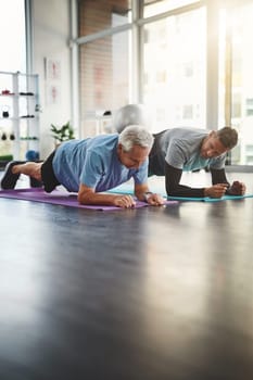 Push up and hold for a few seconds. a young male physiotherapist assisting a senior patient in recovery