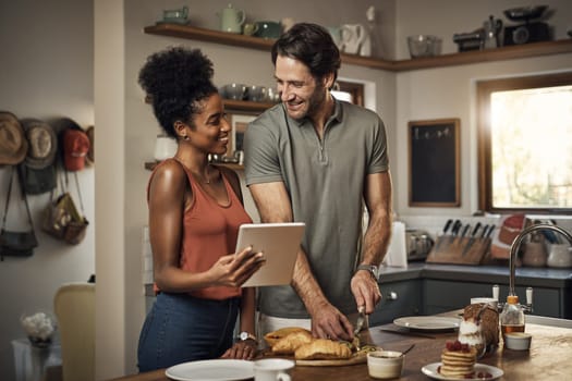 Interracial couple, tablet and cooking in kitchen for recipe, social media or online food vlog at home. Man and woman preparing breakfast meal or cutting ingredients together with technology on table.