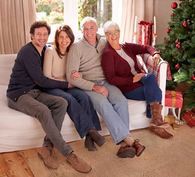Family, christmas and love for holiday celebration with a happy couple and their senior parents together on a living room sofa. Men and women on couch to celebrate christian tradition at home.