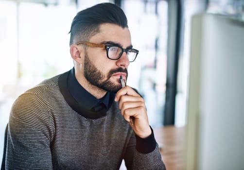 Theres got to be a solution to this challenge...a young designer looking thoughtful while working on a computer in an office