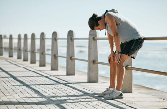 Fitness, tired and breathing man for cardio training, workout or outdoor running break at beach. Breathe, thinking and fatigue of athlete or sports person with exercise challenge in summer by ocean.