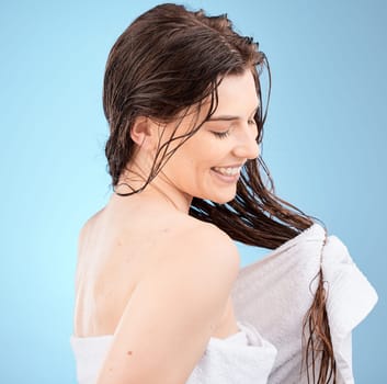 Haircare, washing and cleaning hair and a woman drying her hair with a towel on a blue studio background. Salon, hair style and hair care with a clean female after hair wash with wet hair.