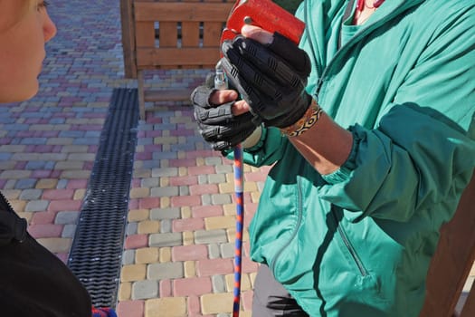 instructor explains how to use belay carabiners with ropes. On the obstacle course in the children's park. Hands with carabiner close up