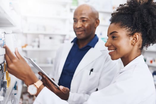 Dispensing with teamwork. two pharmacists doing inventory in a pharmacy with a digital tablet