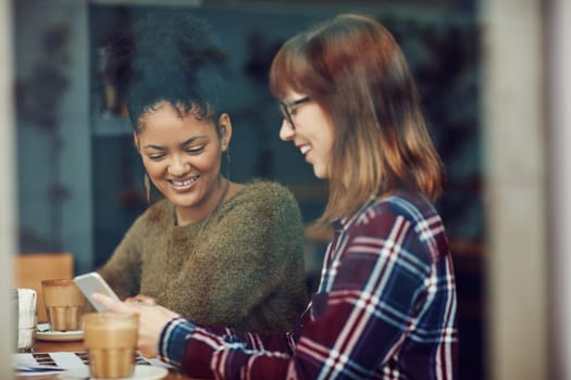 This is the app I was telling you about...two young friends looking at something on a cellphone in a cafe