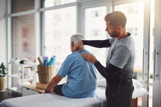 Are you feeling any discomfort over here. a young male physiotherapist assisting a senior patient in recovery