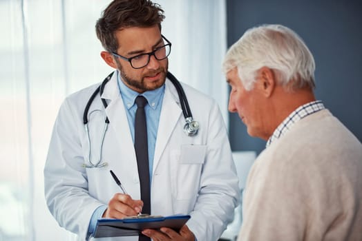 Tell me more about the pain youve been feeling...a doctor writing notes while examining a senior patient in a clinic