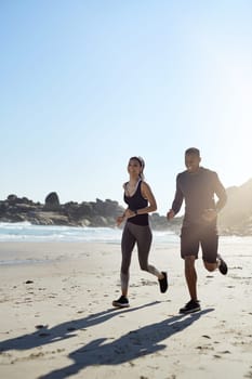 Who needs the gym when you can workout with a view. a sporty young couple out for a run along the beach