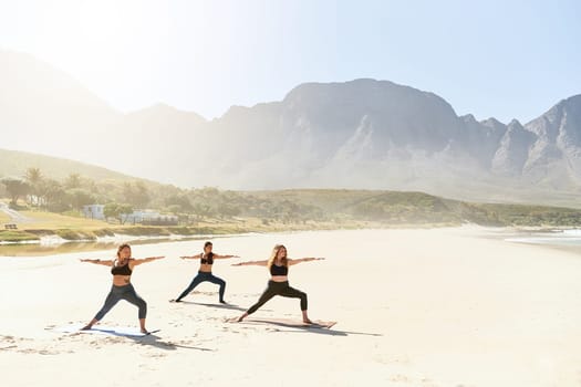 Yoga is an art which connects our soul, mind and body. three young women practicing yoga on the beach