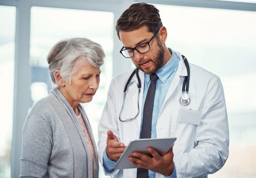 Using technology to better explain her diagnosis. a doctor discussing something on a digital tablet with a senior patient in a clinic