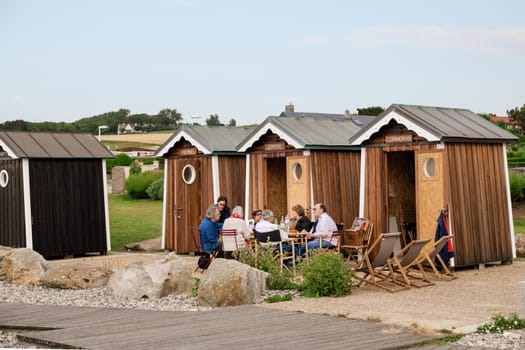 SAINTE-MARGUERITE-SUR-MER, FRANCE - JULY 01, 2018: People at a picnic near their wooden houses or bathing cabins on the Atlantic ocean