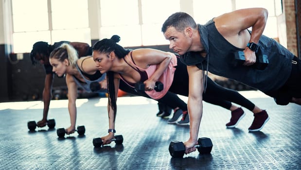 Its hard to beat someone who never gives up. a fitness group using dumbbells in their session at the gym