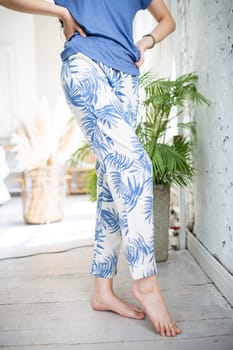 close-up of female legs in homemade blue pants with palm leaves.