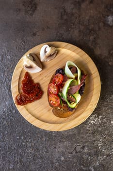 close-up of black bread bruschetta with tomato and cucumber on a wooden plate