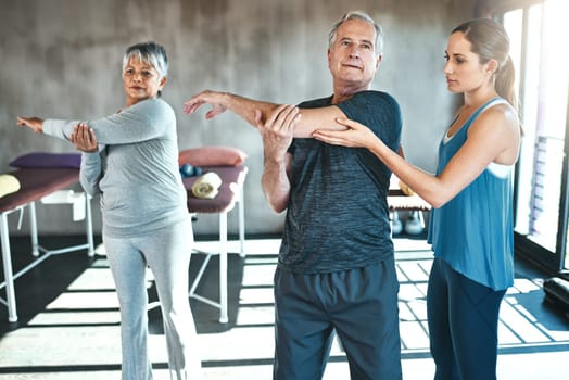 Stretching, physical therapy and old man with personal trainer for fitness, wellness or helping. Health, workout or retirement with senior patient and physiotherapist in class for warm up training.