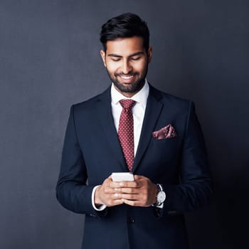 Keeping his career on track by staying connected. Studio shot of a young businessman using a mobile phone against a gray background