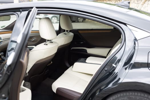 Rear leather passenger seats in modern lux car. White leather car passenger seat. Control unit with electric seat adjustment media system for rear passengers in luxury car. Modern car interior detail.