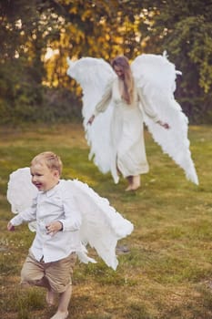 Olstrup, Denmark, June, 2023: Girl angel with her son in the evening garden