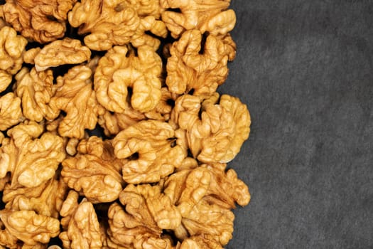 Walnuts. Walnut kernels on dark stone table. Top view, flat layout with space for copy.