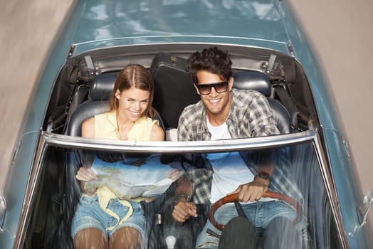 Roadtrip of our dreams. High angle view of a young man driving a convertible with his girlfriend next to him