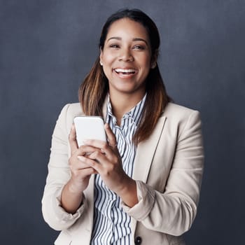 Take a chance and see what happens. Studio shot of a young businesswoman using her cellphone against a grey background