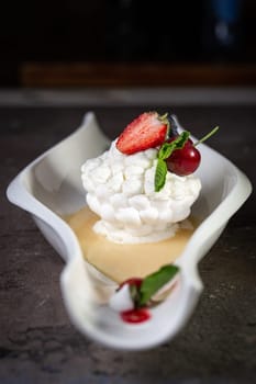 sweet meringue dessert with strawberry berries close-up on a dark background.