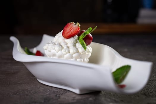 sweet meringue dessert with strawberry berries close-up on a dark background.