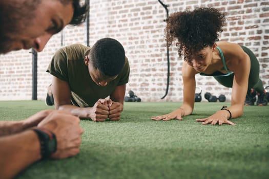 Joining group exercises diversifies your fitness routine. a fitness group planking while working out at the gym